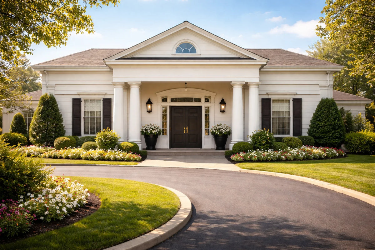 a funeral home with white siding and dark wooden doors on a sunny day