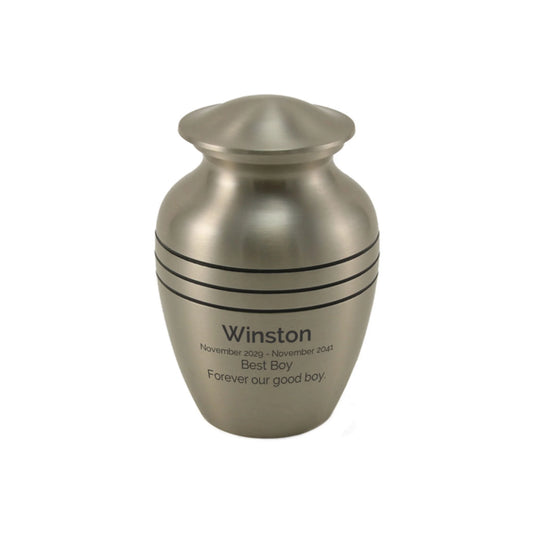 Pewter-finish brass cremation urn front view on white background with accessories laid out