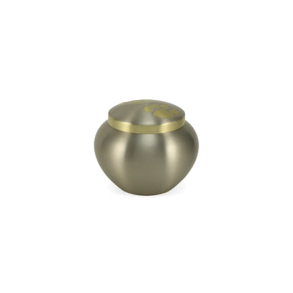 Metal pet urn with a brushed pewter finish and a gold-colored lid embossed with paw prints
