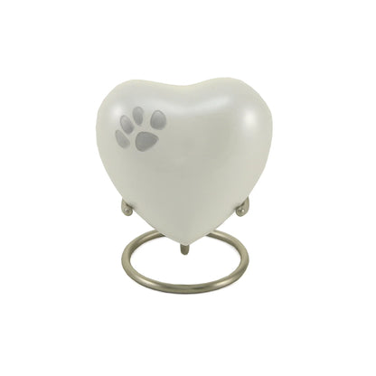 Pearlescent white heart-shaped pet urn featuring a silver paw print design, resting on a matte silver ring stand