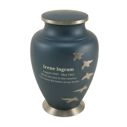 Brass cremation urn with ascending bird silhouettes front view on white background, straight front view