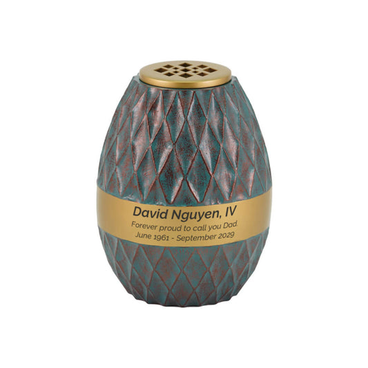 Teal-finish aluminum and brass tall cylindrical scattering urn with diamond pattern upright on white background
