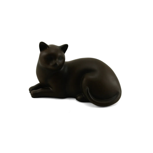 Dark brown ceramic cat sculpture of sleek reclining feline with minimalist features and a curled tail on white studio