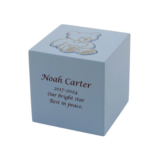 Blue wood-look MDF memorial box urn with teddy bear shape front view on white background